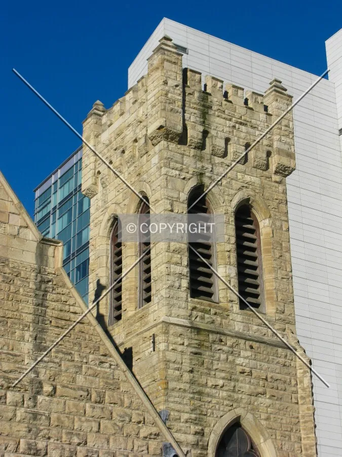 Crenellated tower contrasted against 21st century offices