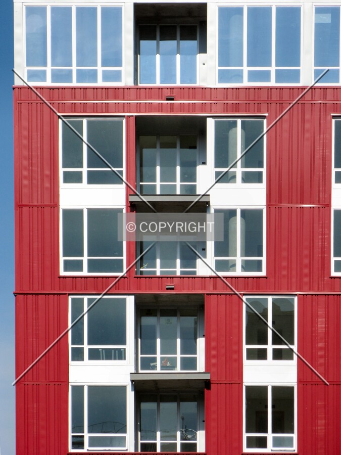 Awaiting balcony railings against the crisp red and gray facade