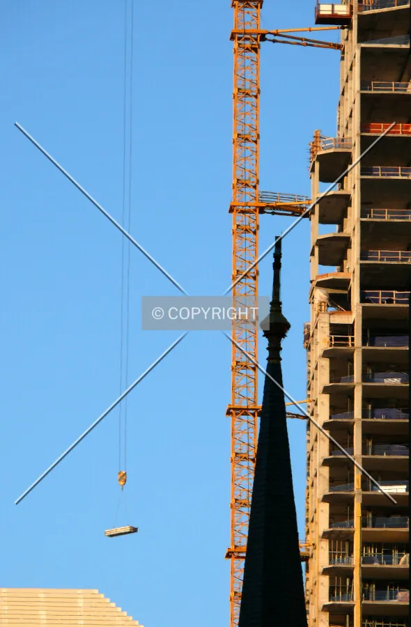 Lowering materials with the top section of steeple of Holy Name Cathedrial visible