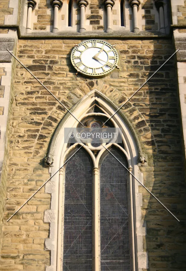A quatrefoil-topped neo-Gothic stained glass window and clock