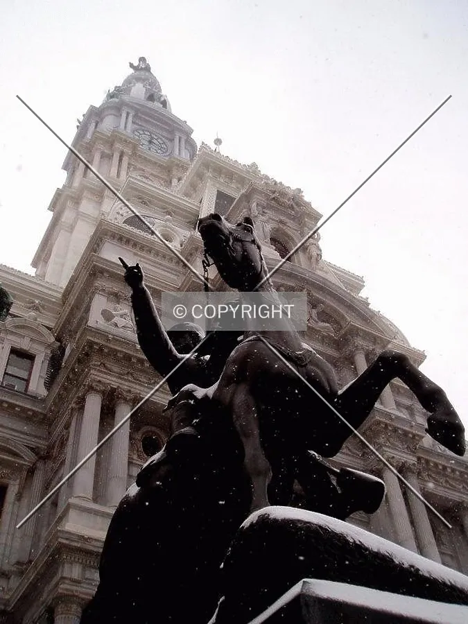 Statues at the base and top of City Hall point to the northeast during a snowstorm