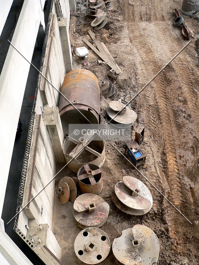 Several caisson drill bits next to the parking structure