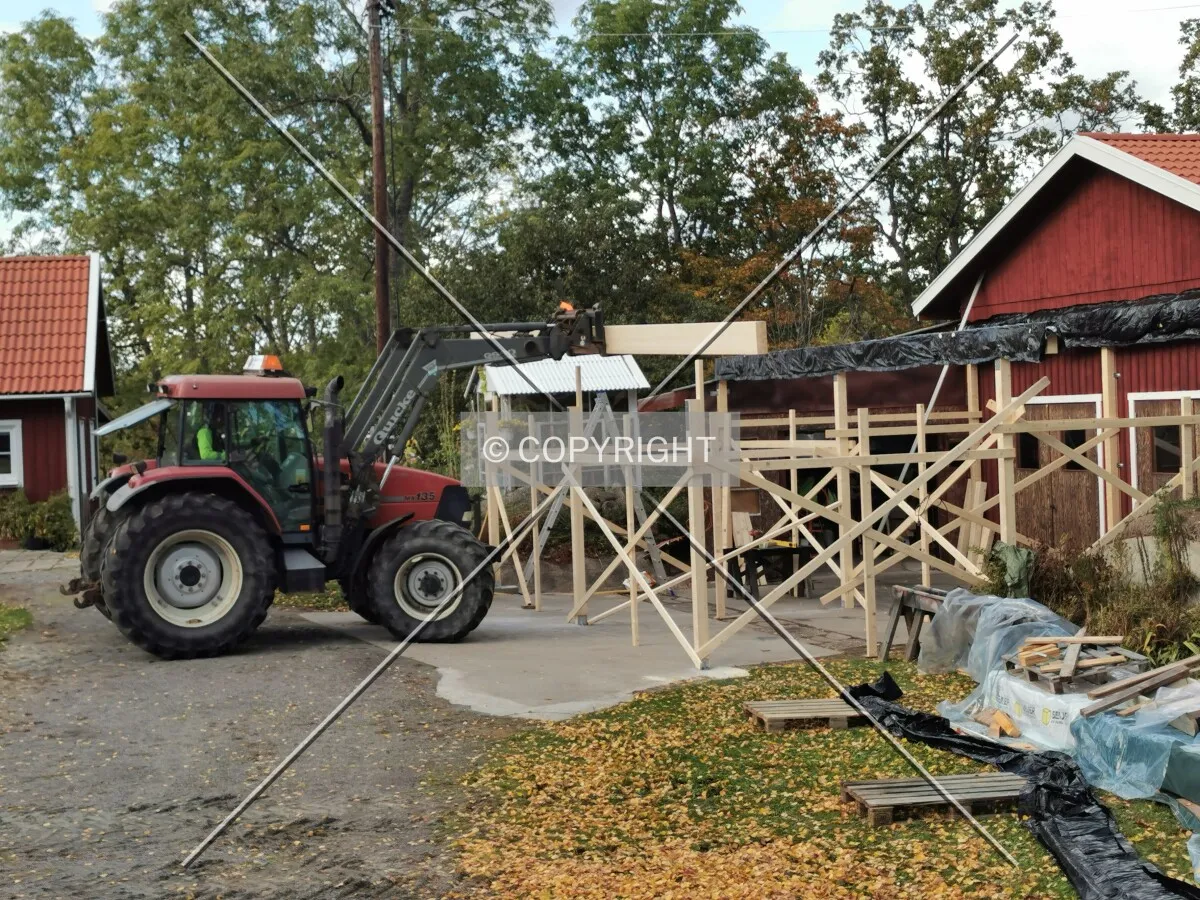 A shed with a wooden framework is constructed using a traktor