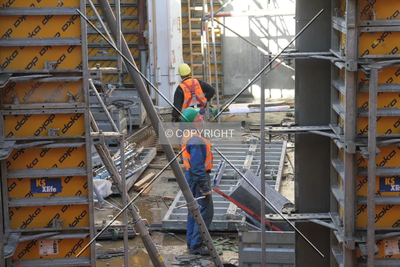 Construction workers between scaffolding and formwork elements