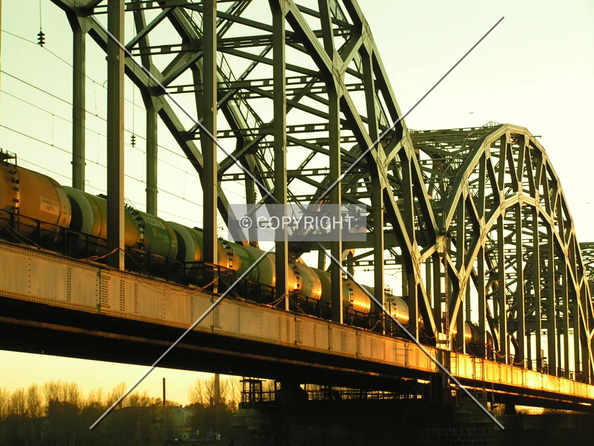 A cargo train passes over a railway bridge spanning the Daugava river