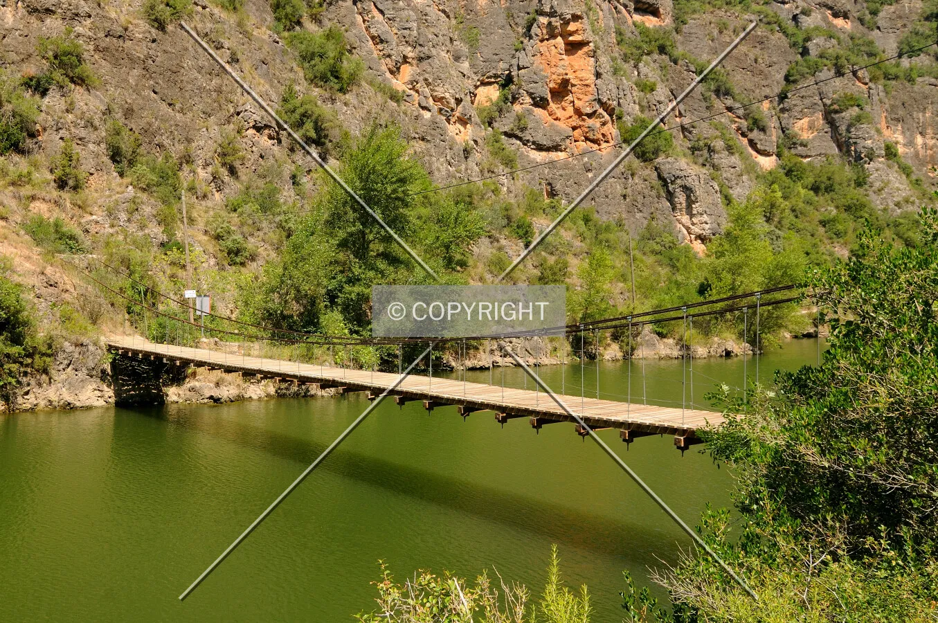 Hanging bridge over Segre River green water