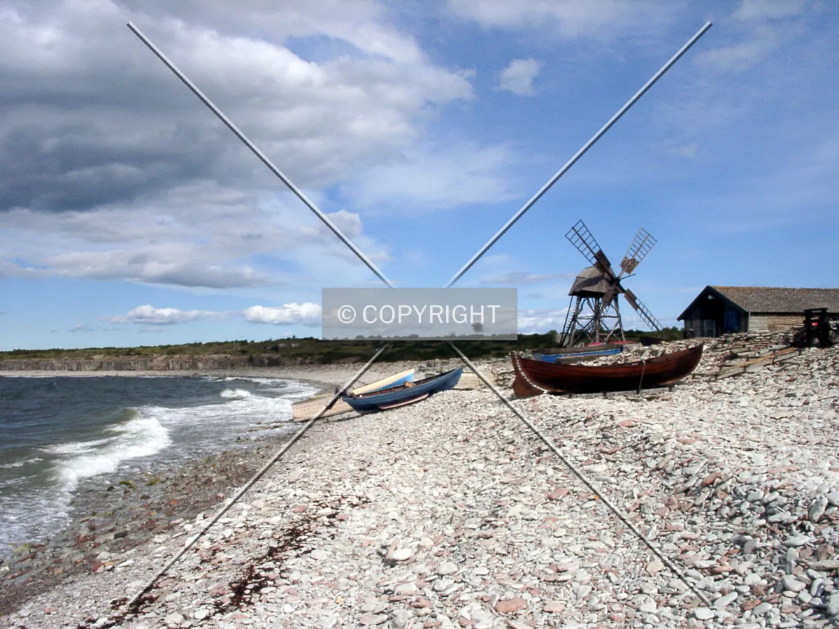 A stony beach with windmill and boat