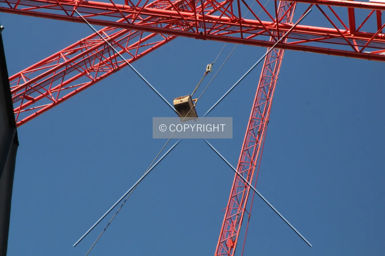 A red construction crane is lifting a container