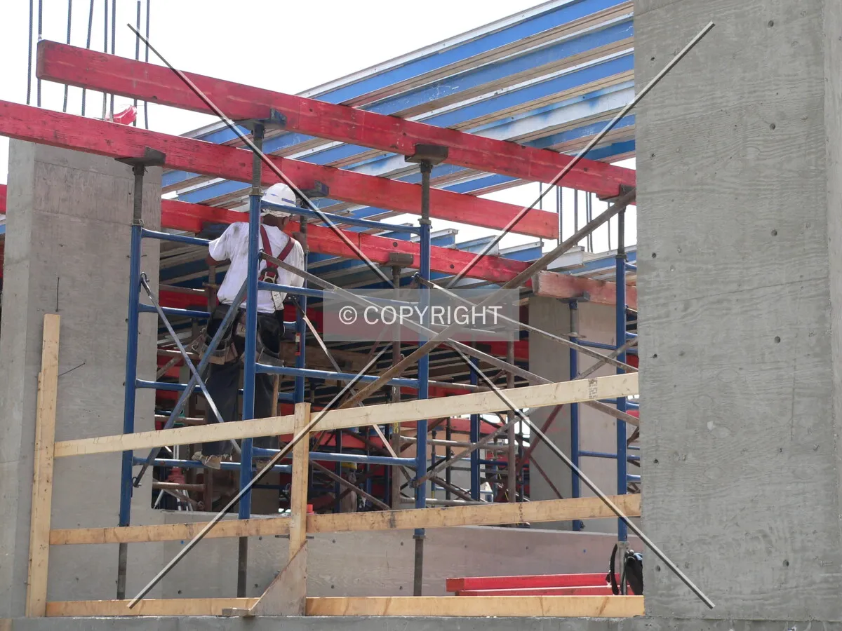 A construction worker installing scaffolding that will help support formwork for the next floor