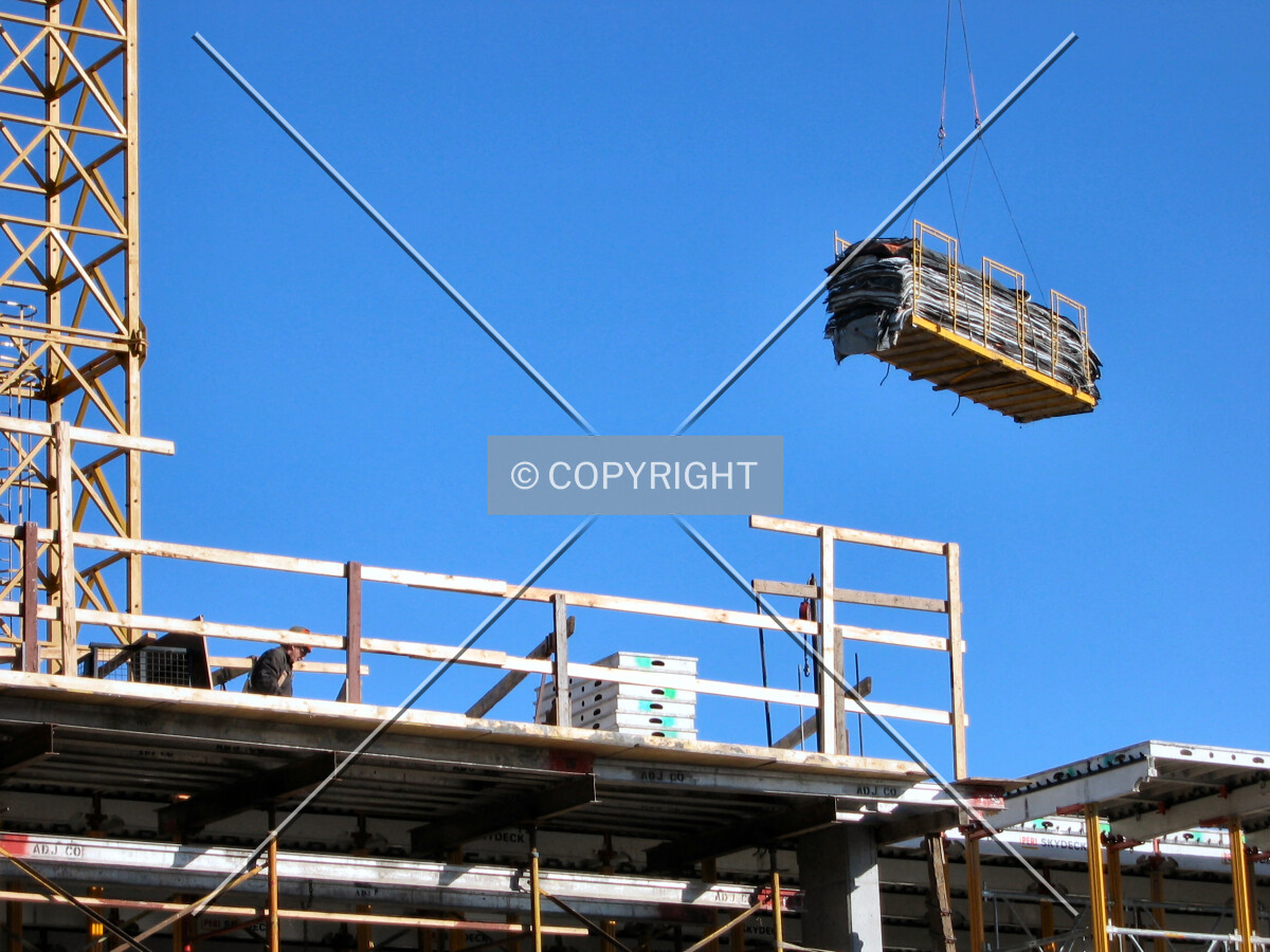 Construction materials being lifted by one of the tower cranes