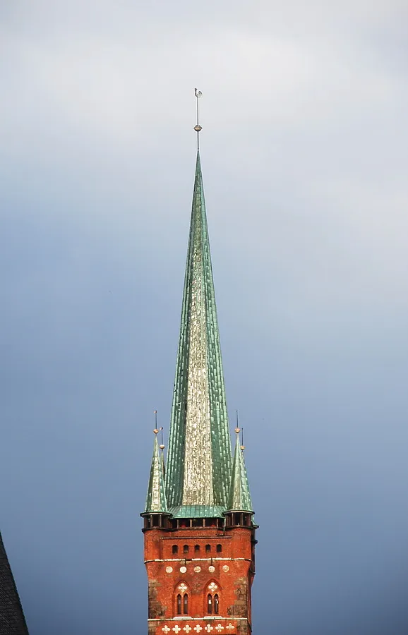 The spire in the sunshine against dark clouds