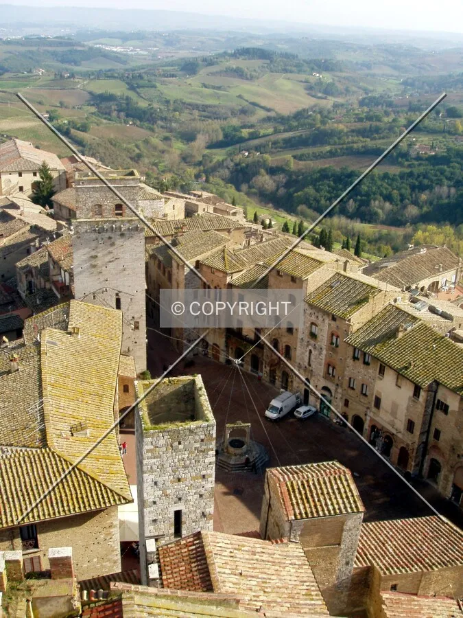 Piazza della Cisterna in foregound and the countryside in the backgound seen from the roof of Torre Grossa