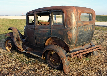 An old rusty car parked in a field