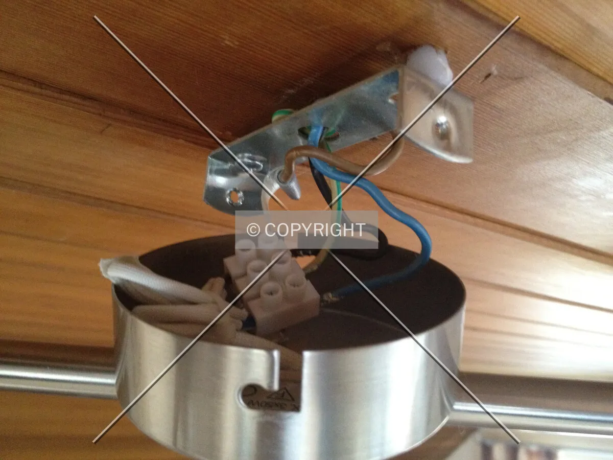 A lamp is being mounted on the ceiling - electrical power connection is attached to the lamp
