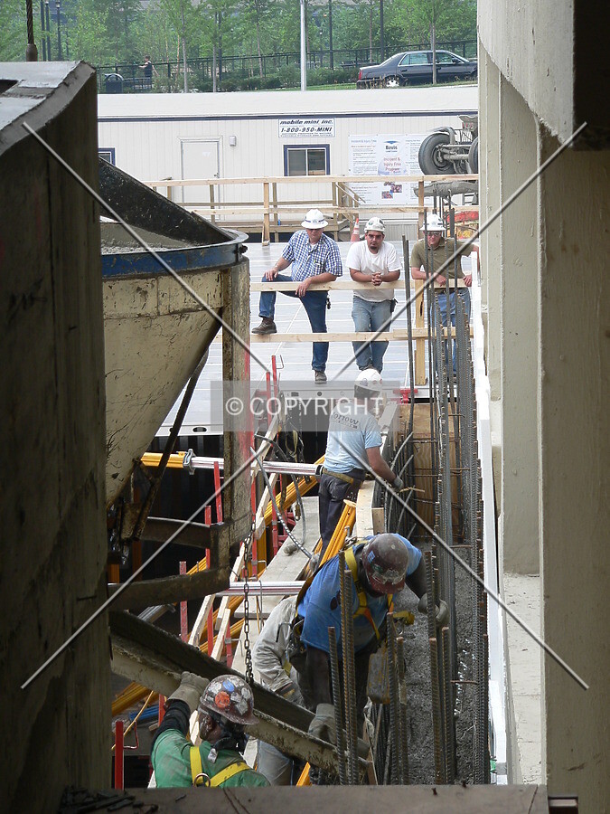 Construction workers pouring concrete and erecting steel reinforcing rebar