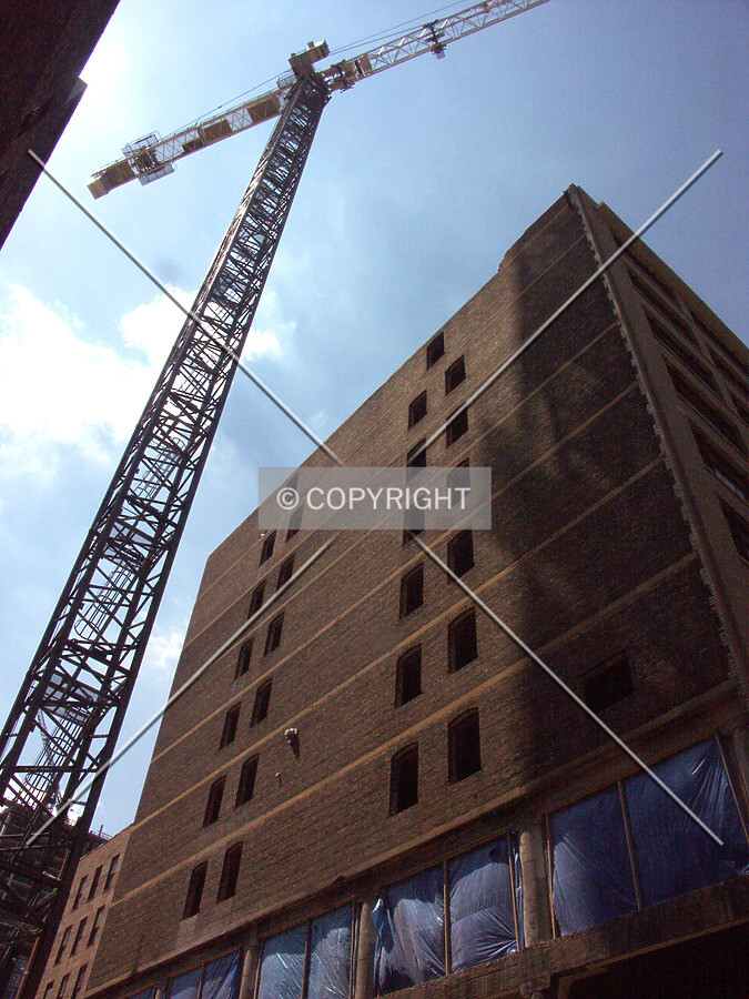 Looking up the south side of the Dwight Building with the tower crane rising from the new foundations