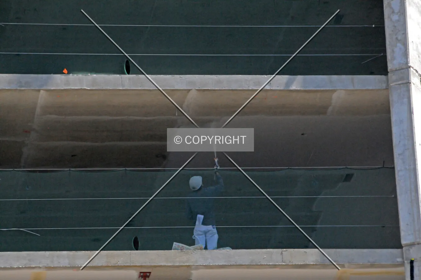 Worker spraying paint onto a ceiling with a spray gun