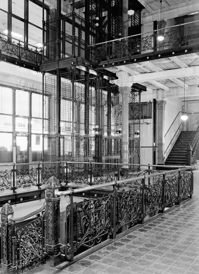 Interior court on the second floor, showing stairwell, ironwork, and exposed elevators