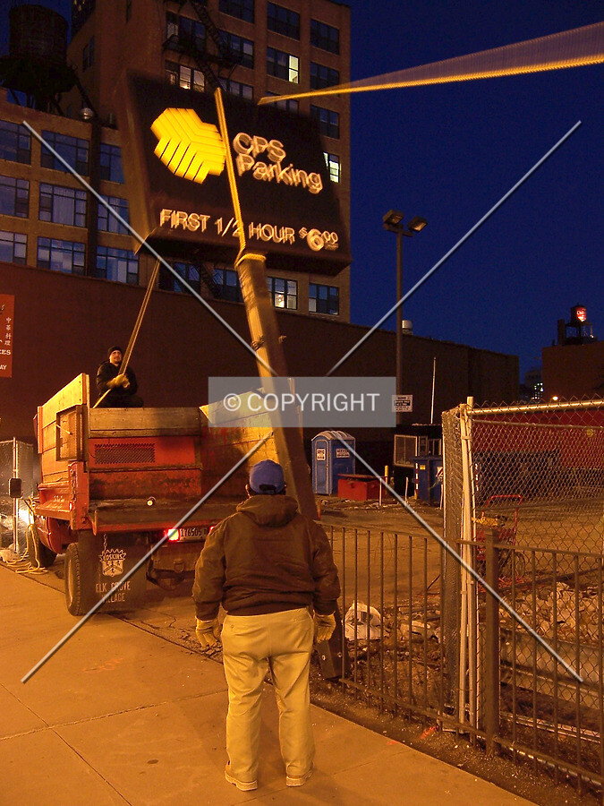 Workers pulling the former surface parking lot sign down