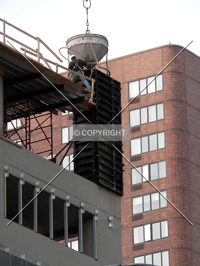 Construction worker pouring concrete into formwork