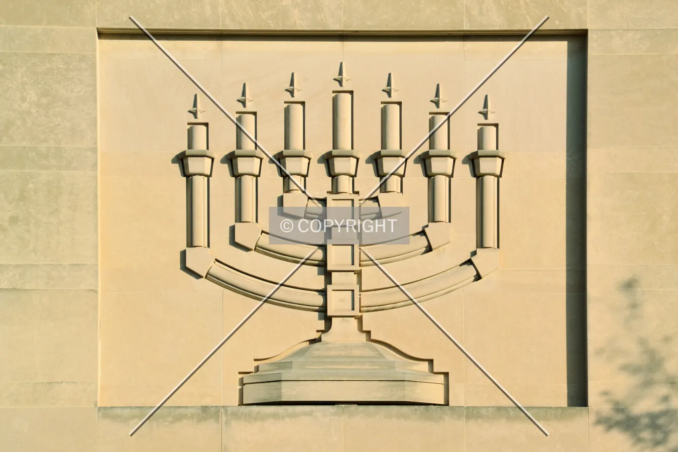 Menorah in limestone relief at the center of the main facade