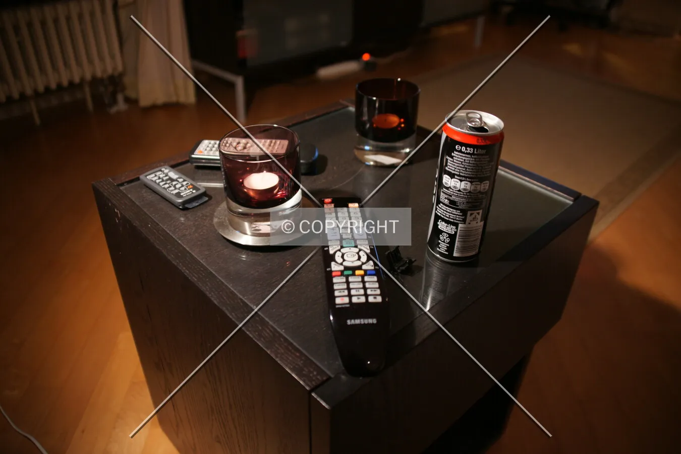 A remote control, candle and can are lying on a couch table