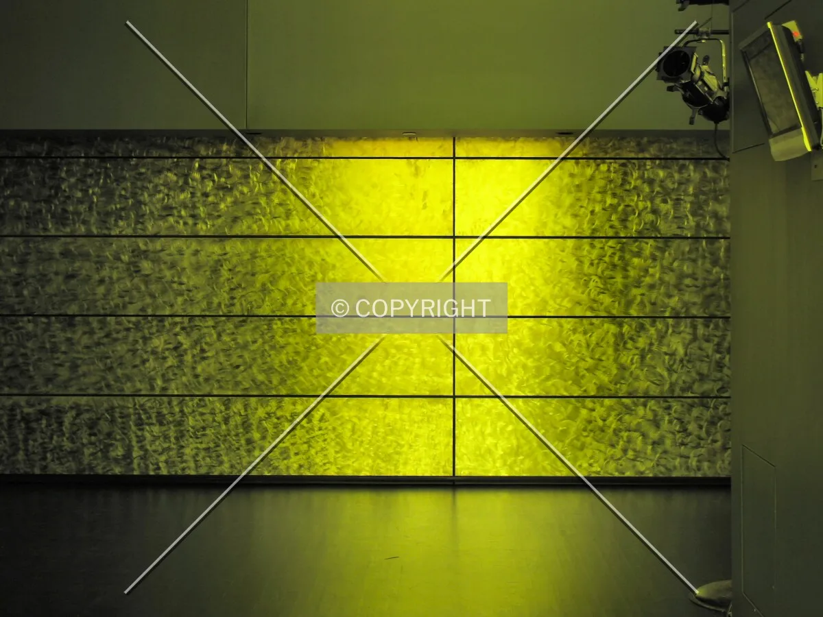 Amber light from colored windows cast onto the metal wall in the Level 9 lobby outside the Dowling Studio