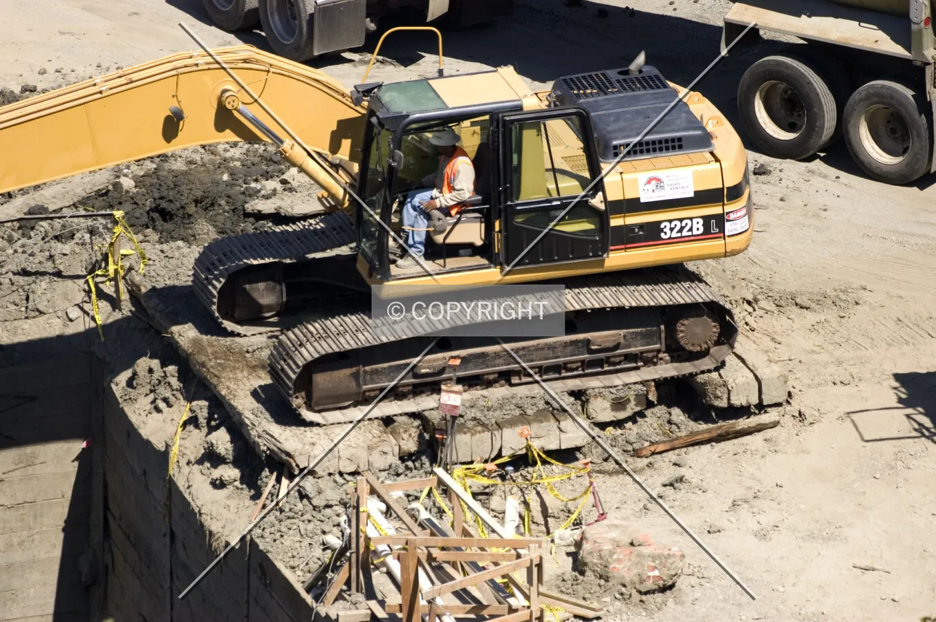 An excavator reaches from the edge of the pit to the final pile of earth below
