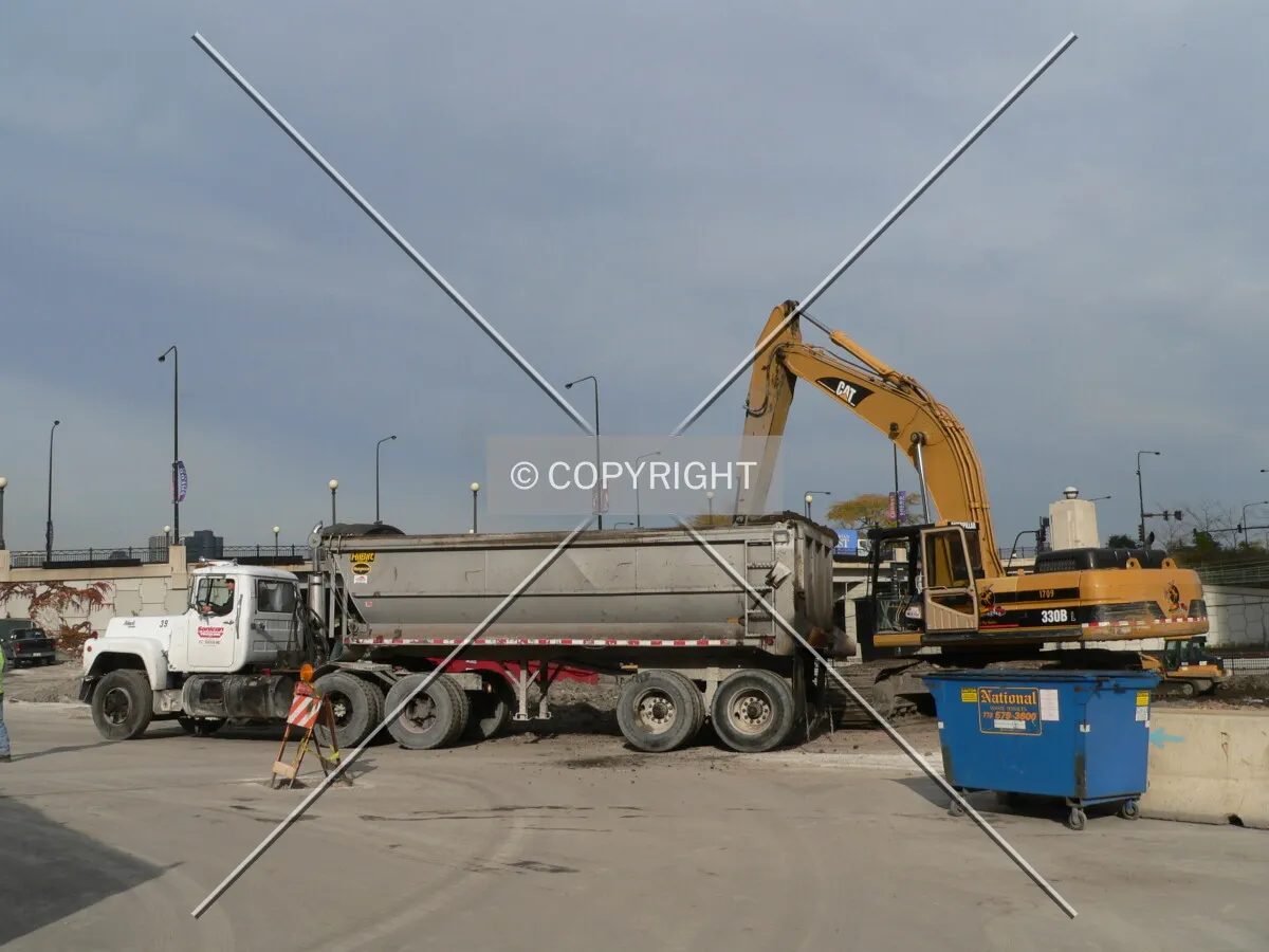 An excavator placing dirt into a dump truck