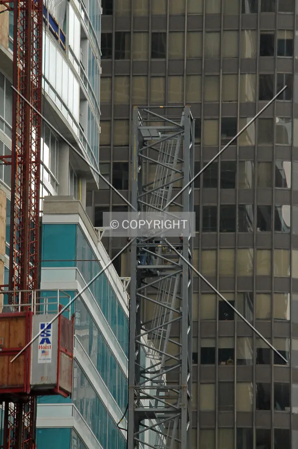 Workers removing bolts to disassemble sections of the tower crane shaft