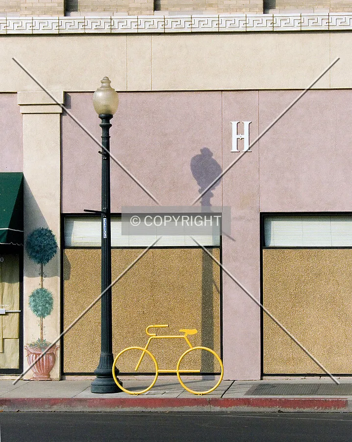 Artwork, a yellow bike sculptor and painted plant, with the "H" on the 17th Street facade
