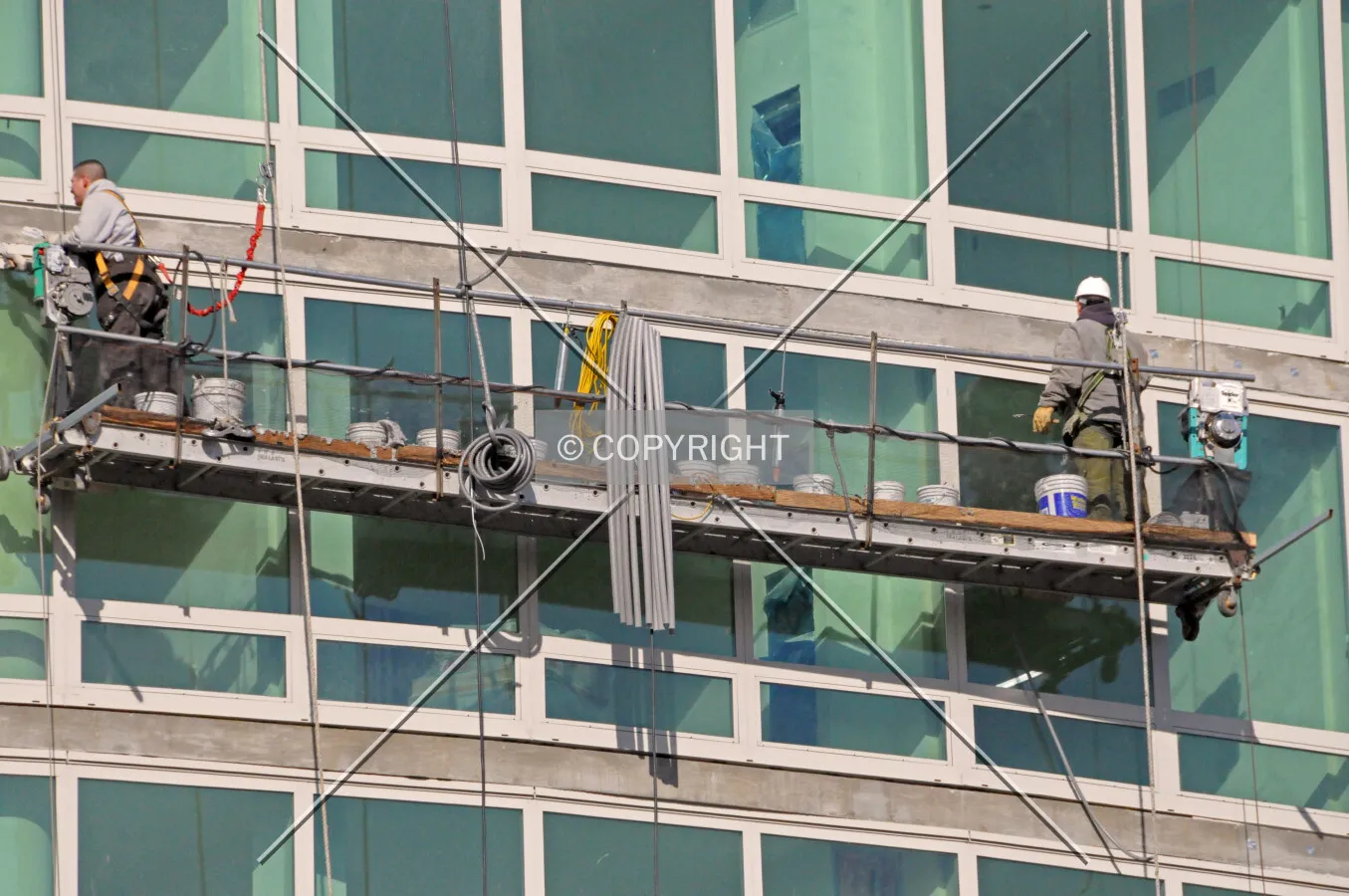 Workers sealing cracks between floor slab edges and the window frames