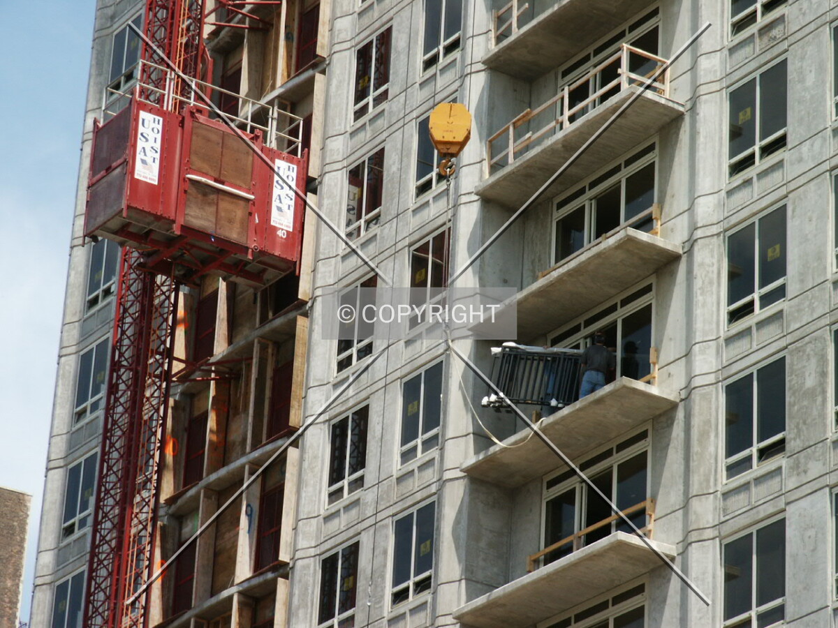 Workers receiving a balcony railing from the tower crane
